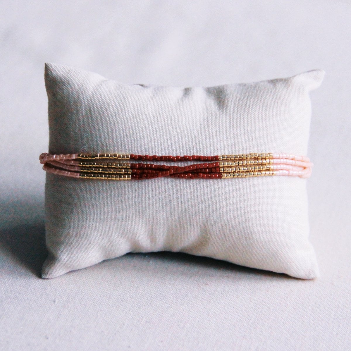 Bazou Viervoudige Miyuki armband in bordeaux, naakt en goudkleurige beads, showing intricate woven design and mixed colors.