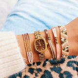 Bazou Viervoudige Miyuki armband in bordeaux, nude, and gold colors with intricate beaded design on a white background.