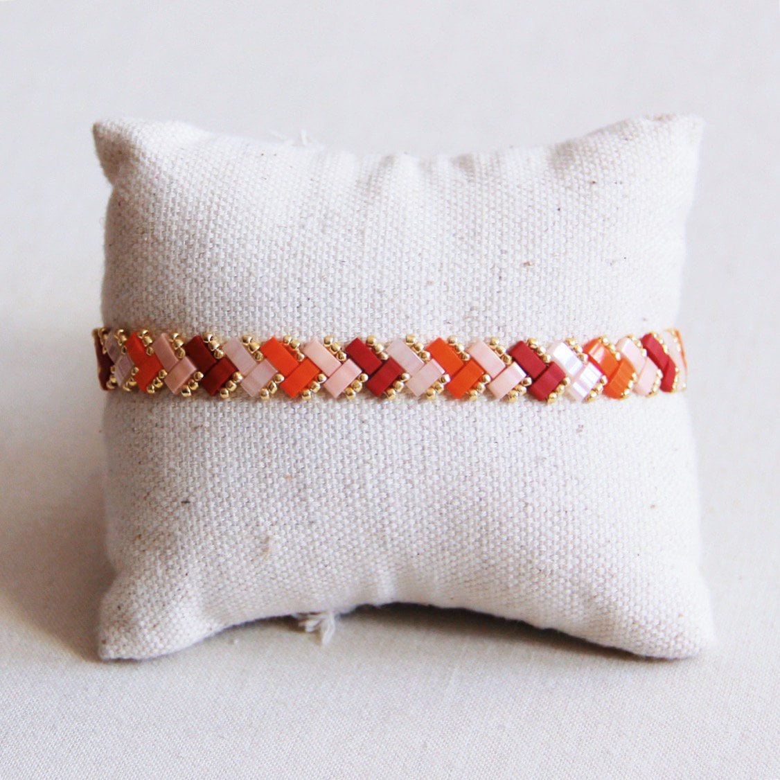 Bazou Gevlochten Tila Kralen armband in zalm, oranje, en bordeaux met woven design and colorful beads.