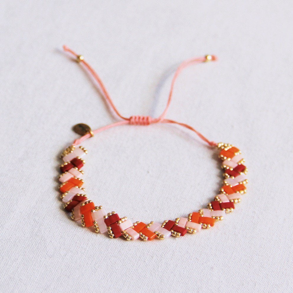 Bazou Gevlochten Tila Kralen Armband in zalm, oranje, en bordeaux with woven design and colorful beads.