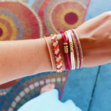 Bazou Gevlochten Tila Kralen armband in zalm, oranje, en bordeaux with woven design and colorful beads.