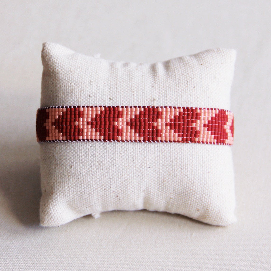 Bazou woven Miyuki armband with heart design in Bordeaux and salmon colors, showcasing intricate beadwork and textured fabric.
